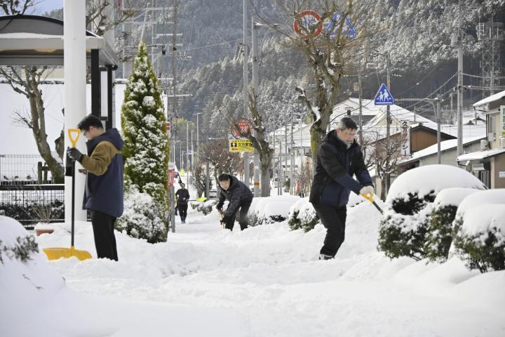 積雪20センチ記録した久万高原町で職場前の雪かきをする男性＝10日午前8時10分ごろ、同町久万