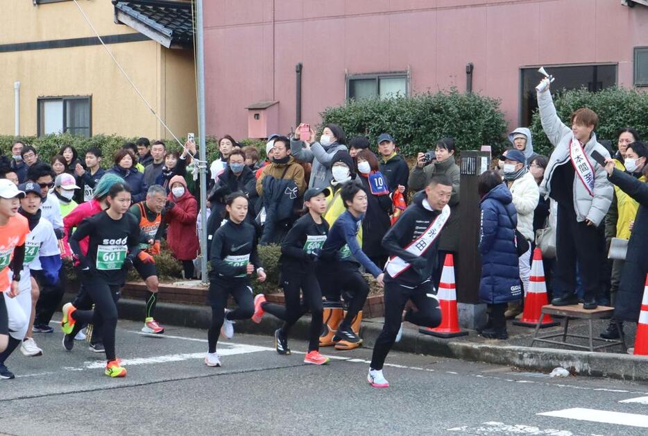 ７０回目の節目となった村上市元旦マラソン。スターターはサッカー選手の本間至恩さん、参加しているのはパラトライアスロン選手の永田務さん＝１月１日、村上市三之町