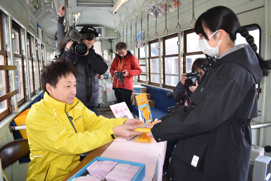 受験生にエールを送りながらお守りセットを手渡す市職員