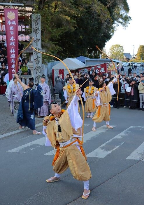 空に向け弓を引き絞る射手