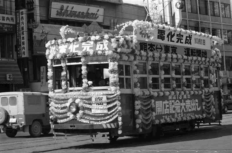 ⑤国鉄の電化を祝う花電車。客車を装飾するタイプで、側面には大洋デパートの「開店13周年　開店記念大売出し」の看板が見える＝1965年10月、熊本市手取本町