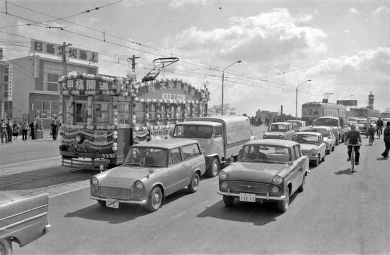 ④大甲橋は熊本市電開業のため架けられた橋の一つ。1953年の「6・26水害」では流失を免れたが、橋桁に流木などが引っかかり、白川があふれる一因となった。写真は架け替え工事を終え、開通を祝って走る花電車＝1965年4月、熊本市水道町