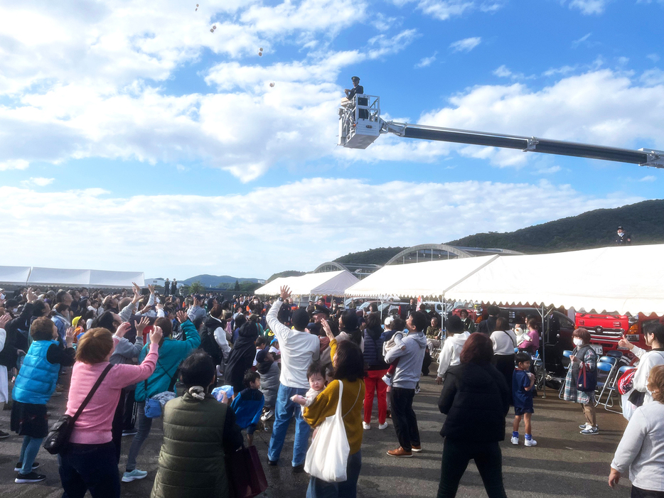 出初め式の餅まきで手を伸ばす住民たち（5日、瀬戸内町古仁屋）