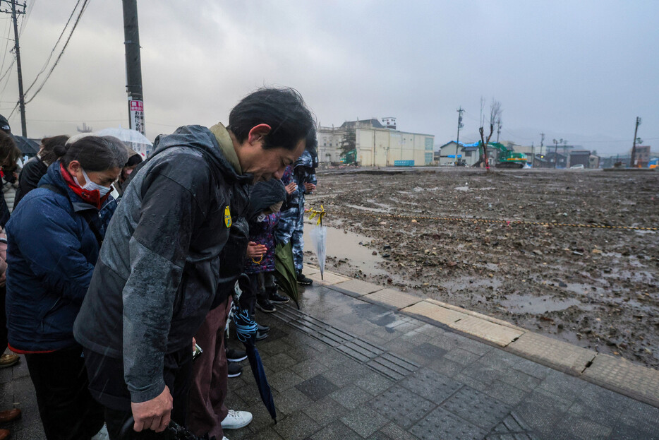 観光名所「朝市通り」付近で、能登半島地震の発生時刻に黙とうする人たち＝１日午後、石川県輪島市