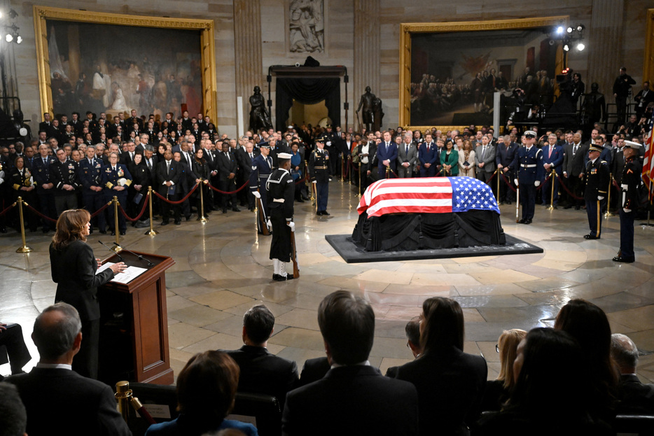 　１月７日、昨年１２月２９日に１００歳で死去した第３９代米大統領のジミー・カーター氏の遺体を収めたひつぎが７日、南部ジョージア州アトランタから首都ワシントンに到着した。写真は、ひつぎの前で弔辞を述べるハリス米副大統領。同日、ワシントンで撮影（２０２５年　ロイター/Saul Loeb）