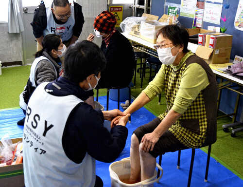 仮設住宅の住人（右）に足湯を提供するなどし、交流を図るボランティアたち（１日午後、石川県穴水町で）＝中川慎之介撮影