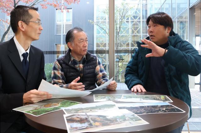 被災地の写真を前に当時の状況などについて話す（右から）戸高明廣主幹、川野隆志さん、尾山直人主幹＝小林市役所