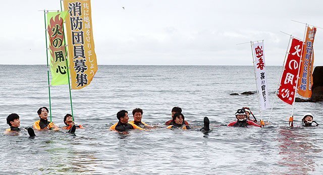 海に入り、のぼり旗を掲げる潜水隊員