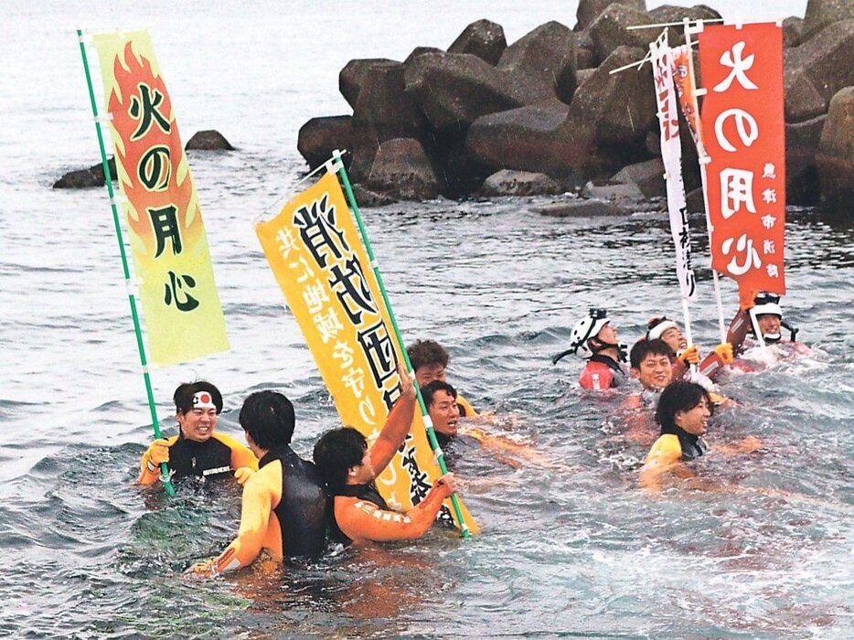 海に入ってのぼり旗を掲げる潜水隊員＝大町海岸