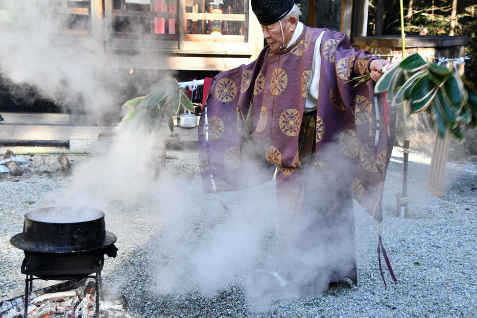 湯気を引くササを持って舞う大井貞夫宮司＝眉間伊賀市の岡八幡宮で、大西康裕撮影