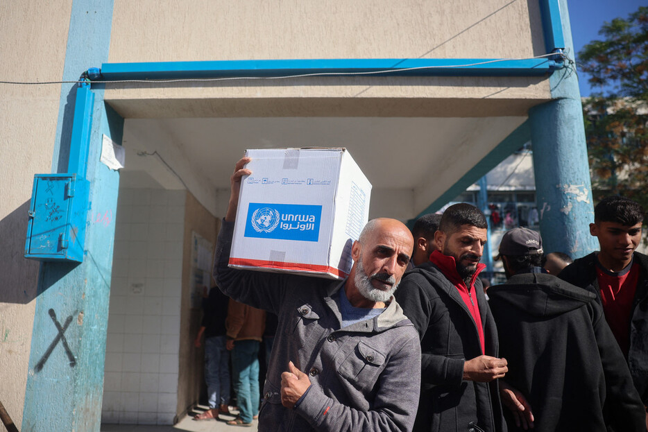 国連パレスチナ難民救済事業機関（ＵＮＲＷＡ）からの物資を運ぶ男性＝２０２４年１２月、パレスチナ自治区ガザ（ＡＦＰ時事）