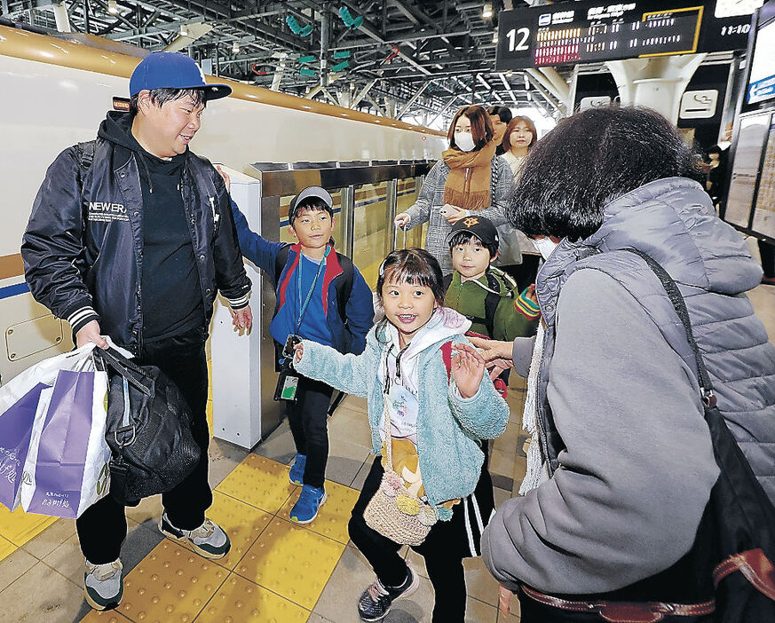 ふるさとの親族の見送りを受けながら、笑顔で東京行きの新幹線に乗り込む家族＝４日午前１１時１０分、ＪＲ富山駅