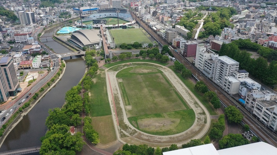 再配置が検討されている市民総合プール（中央左上）と陸上競技場（手前）。右上の丘は平和祈念式典が開かれる平和祈念像前＝昨年６月、長崎市（小型無人機ドローン「空彩４号」で撮影）