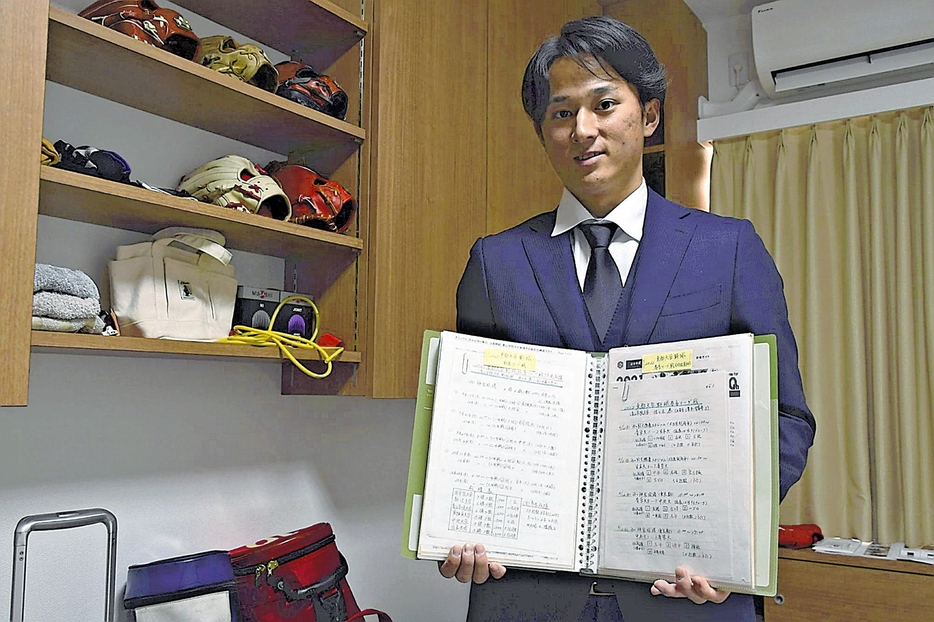 寮の自室で祖父が作成した冊子を手にする佐々木選手（広島県廿日市市で）