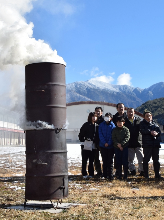 住民が見つめる中、空高く上がる煙