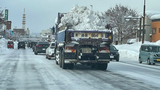 夜通し除雪作業が行われ何台もの大型トラックが雪を運んでいる（3日午前　青森市）