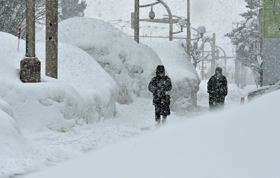 除雪された雪の中を歩く人たち＝９日午後、青森市