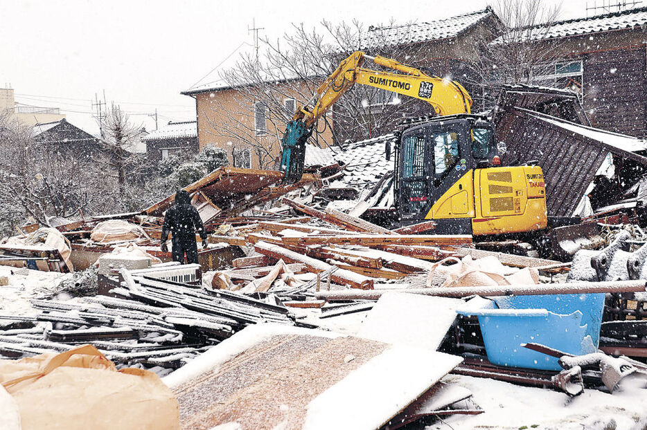 雪の中、被災家屋の解体作業を急ぐ重機＝８日午前１１時、輪島市鳳至町