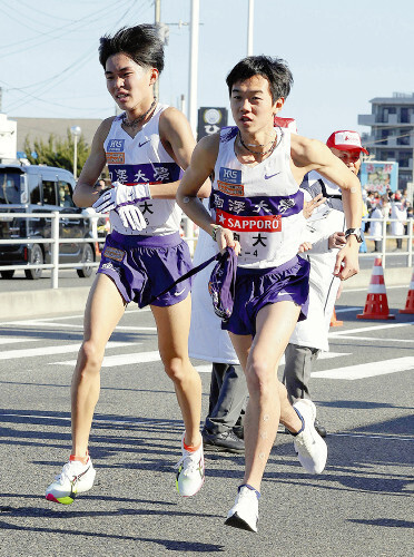 平塚中継所でたすきをつなぐ駒大３区の谷中晴（左）と４区の桑田駿介