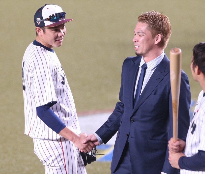 2019年のプレミア12で、試合前にスーツ姿で訪れた前田健太（中央）と握手を交わす坂本。右には山田がチラリ