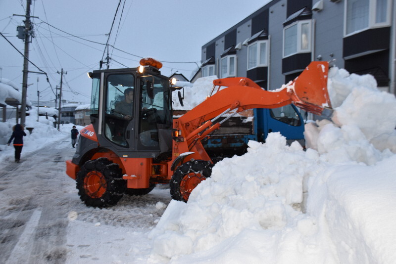 アパートの駐車場に降り積もった雪をブルドーザーで片付ける除雪業者＝青森市で2025年1月8日午後4時27分、江沢雄志撮影