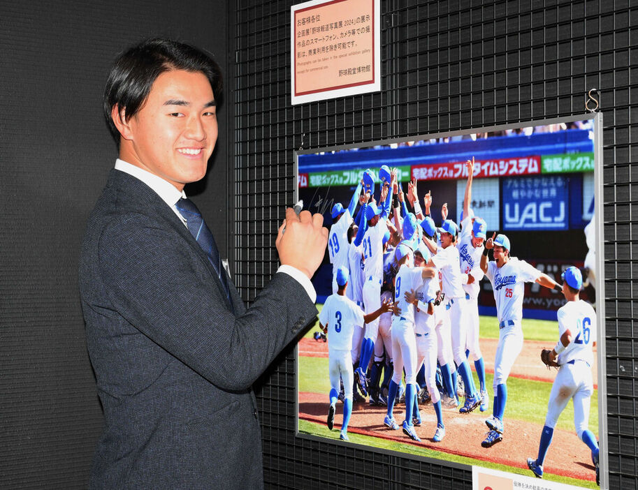 野球報道写真展に展示中の写真にサインをするロッテ・西川史礁＝東京・文京区の野球殿堂博物館（代表撮影）