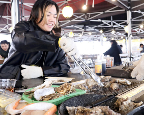 網の上でカキを焼く客（４日、前橋市で）