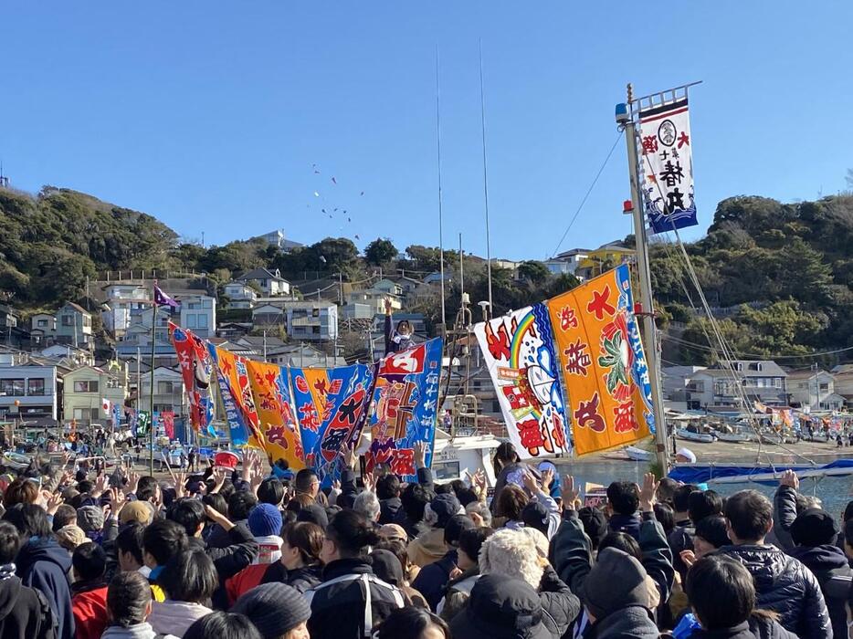 小坪漁港の遊漁船から投げられる福みかんや菓子などを求めて多くの市民が集まる