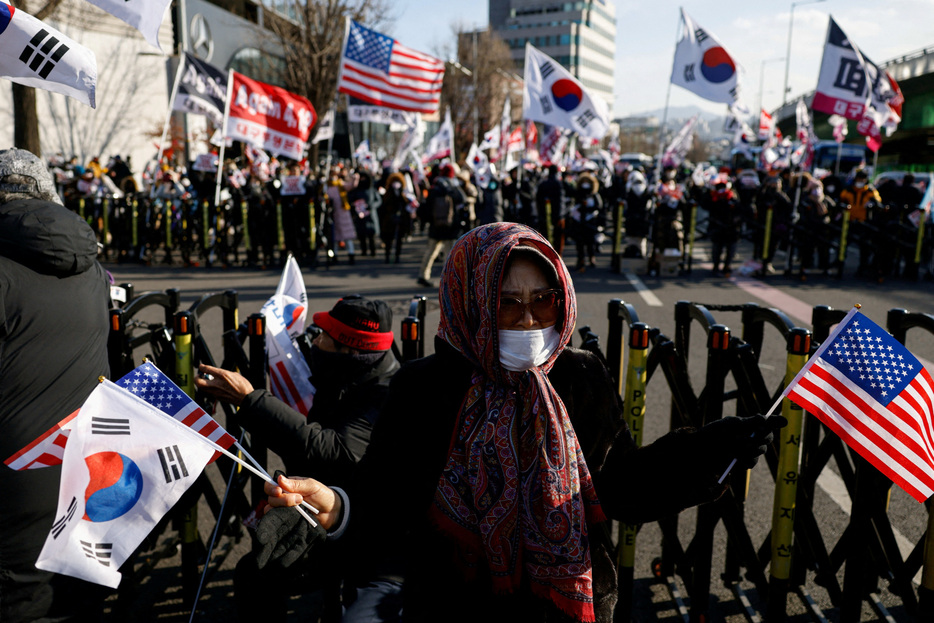 弾劾訴追され職務停止となった韓国の尹錫悦大統領の拘束が実現せず、先行き不透明感が増していることで、尹氏の支持者が勇気づけられ、与党「国民の力」の支持に回復の兆しが見られている。大統領支持派のデモ、ソウルの大統領官邸近くで９日撮影。（２０２５　ロイター/Tyrone Siu）