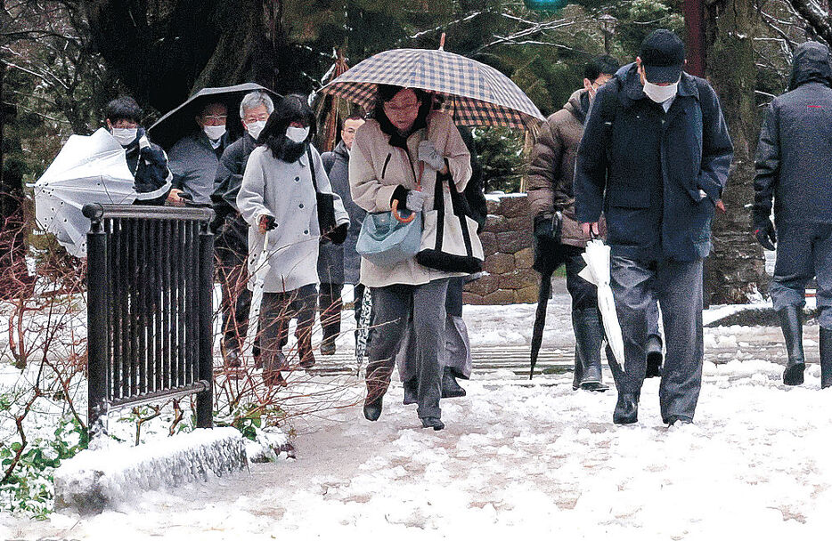 歩道に雪が積もり、足元を気にしながら歩く人＝９日午前８時１５分、金沢市広坂１丁目