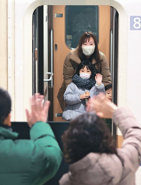 北陸新幹線の発車間際、見送りの祖父母に手を振る女の子＝富山駅（草東良平撮影）