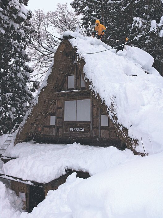 屋根の雪下ろしに励む職員ら＝相倉合掌造り集落