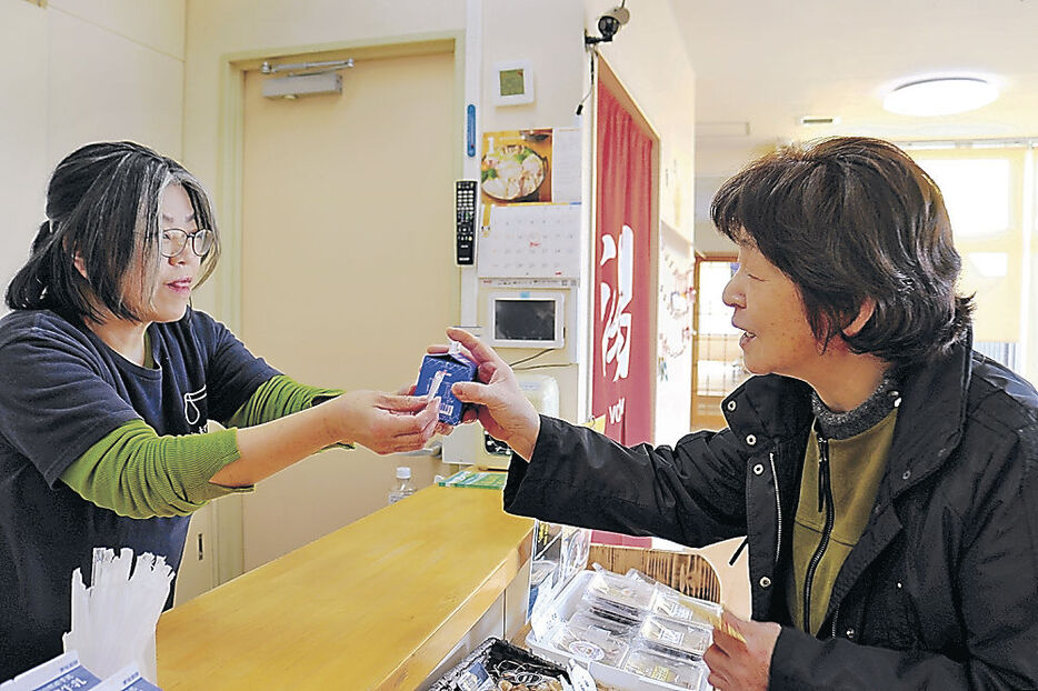 牛乳を受け取る入浴客＝富山市水橋中村町花内の水橋温泉ごくらくの湯