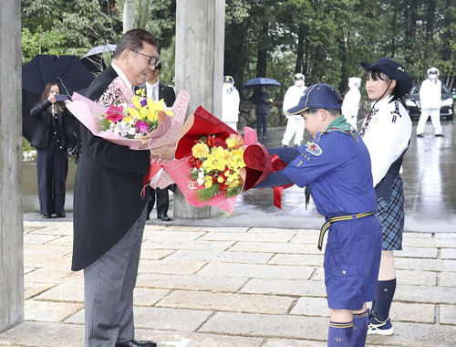 【子どもらから花束を受け取る石破首相（左）＝伊勢市宇治館町の神宮司庁玄関前で】