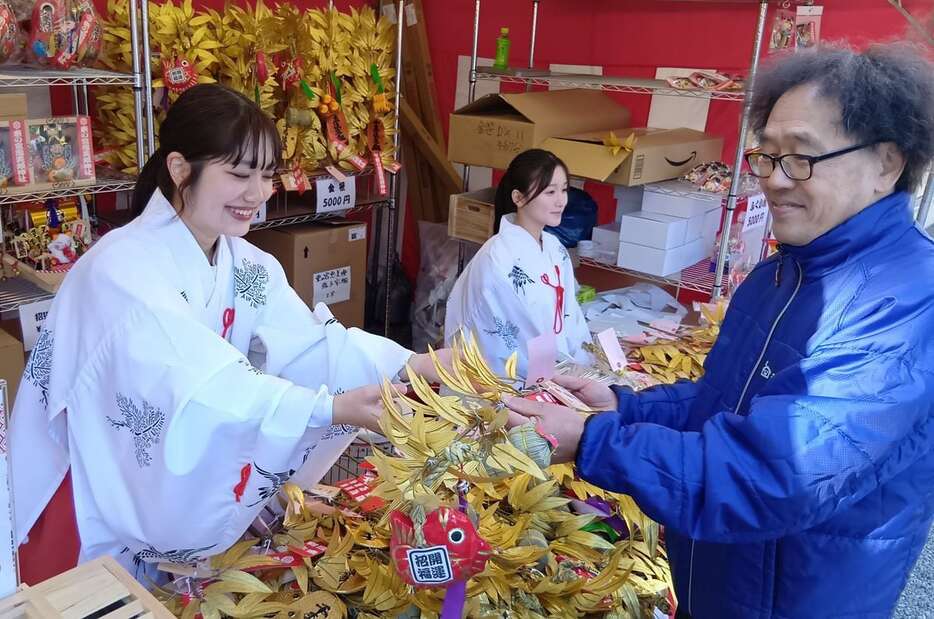 東の宮恵美須神社の「十日戎」で参拝者（右）に「金笹」を授ける福娘＝和歌山市