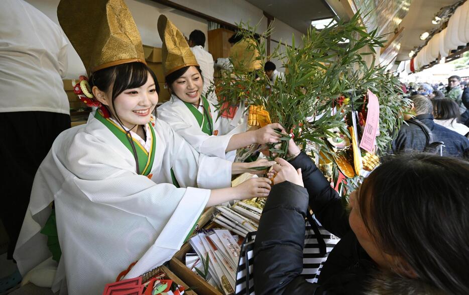 大阪市浪速区の今宮戎神社で「十日えびす」の幕開けとなる「宵えびす」が始まり、縁起物を結び付けた「福ザサ」を参拝客に笑顔で手渡す福娘たち。10日の「本えびす」では、大阪・ミナミの繁華街を練り歩く「宝恵かご行列」が開催される＝9日午後