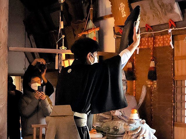 ブリを掲げる神社委員の野口さん