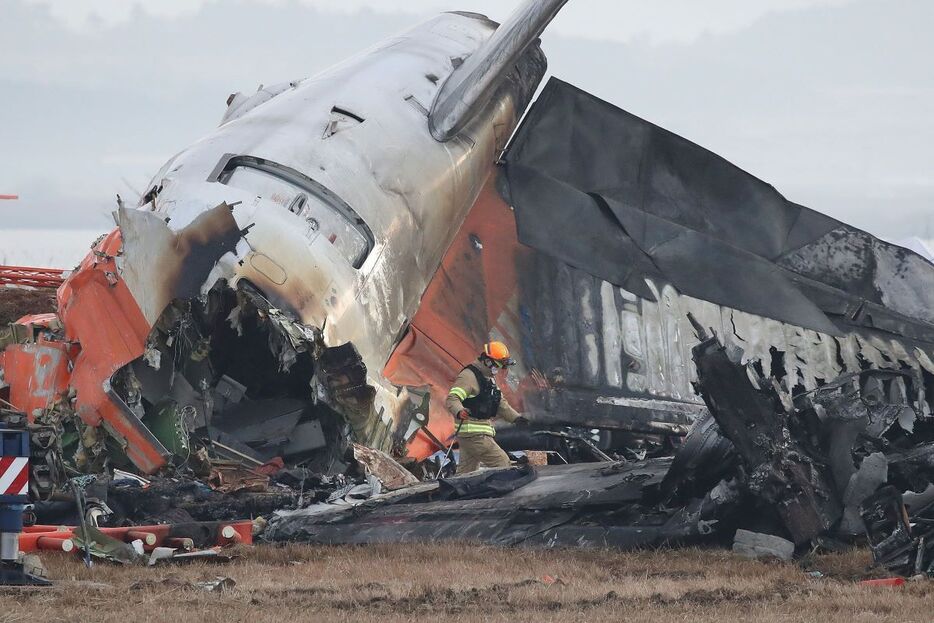 務安国際空港に墜落した旅客機の残骸の周辺で作業する消防隊員