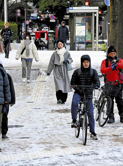 雪が積もった歩道を歩く人たち（10日午前、福岡市・天神で）＝足立浩史撮影