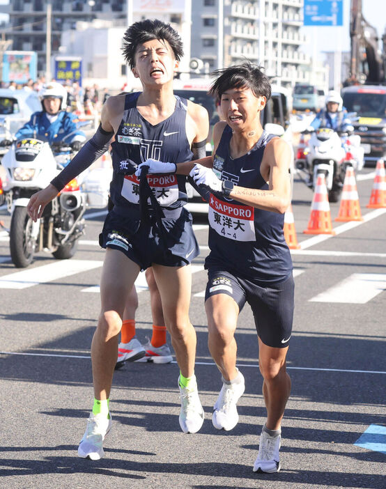 平塚中継所でタスキをつなぐ東洋大３区の迎暖人（左）と東洋大４区の岸本遼太郎（カメラ・池内　雅彦）