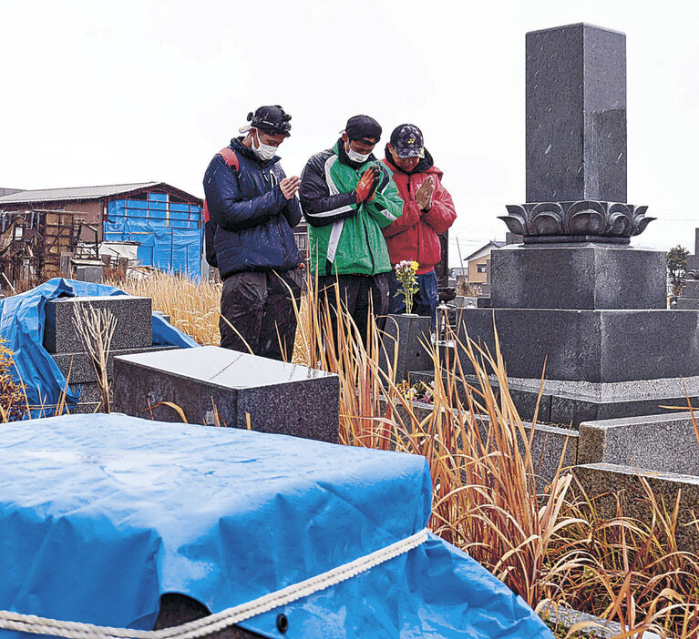 能登半島地震の発生１年を前に家族の墓に手を合わせる人＝３１日午後０時２０分、珠洲市宝立町春日野