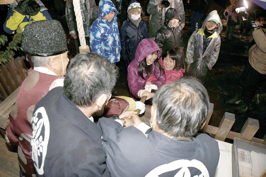 宇治橋宮司らとねんじり棒を引き合う子供たち