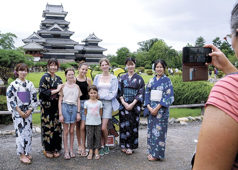 松本城を背景に記念撮影をする外国人旅行客ら（昨年7月30日）