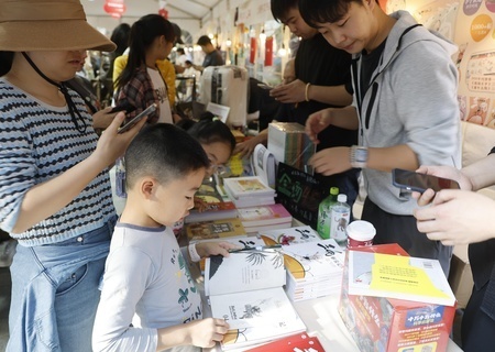 上海市である公園で開催されたフリーマーケットで本を読む子ども（2024年10月3日撮影、資料写真）。