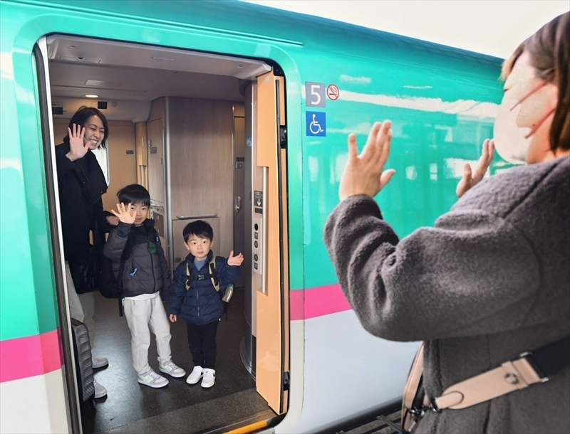 親族に見送られて手を振る子ども＝５日午前９時４０分ごろ、ＪＲ福島駅新幹線ホーム