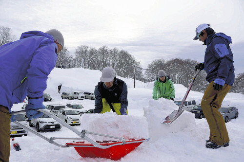 屋根に積もった雪を下ろす人たち（６日、青森市の酸ヶ湯温泉で）