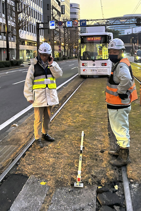 路面電車が脱線した現場付近を調べる熊本市交通局の職員ら＝2024年12月、熊本市中央区