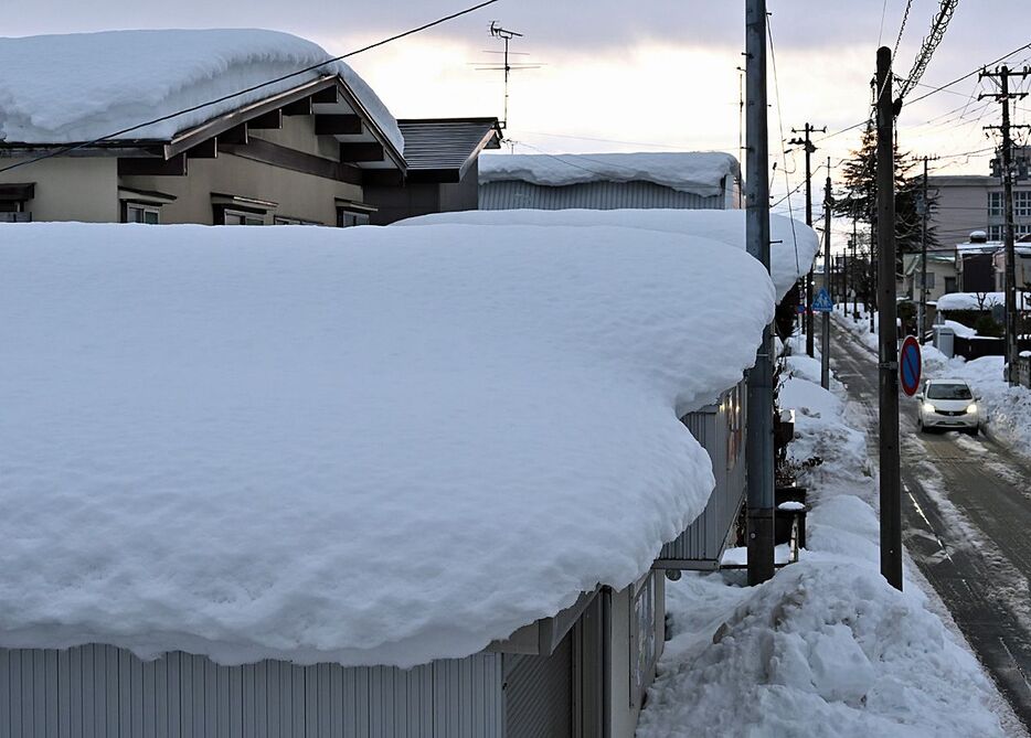 12月から続いた降雪の影響で家屋やガレージ等の屋根に積もる雪＝7日午後4時19分、青森市浪打1丁目