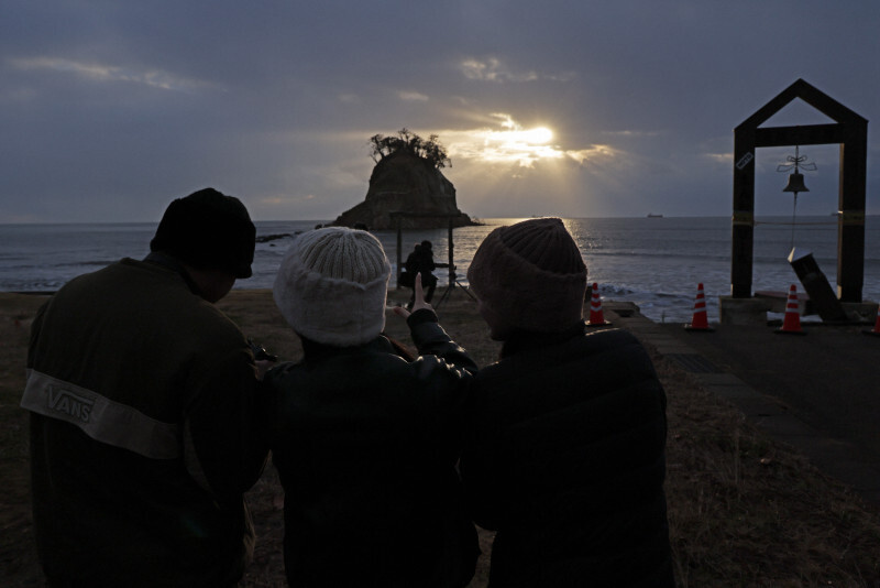 能登半島地震から1年となる元日、初日の出を見つめる人たち。「珠洲が安心して帰れる場所であってほしい」と話した。地元住民や帰省した家族らが海岸に集まった＝石川県珠洲市で2025年1月1日午前7時50分、和田大典撮影