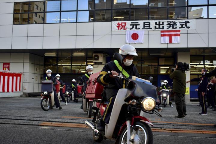 一斉に出発する配達員＝1日午前8時半ごろ、松山市三番町3丁目